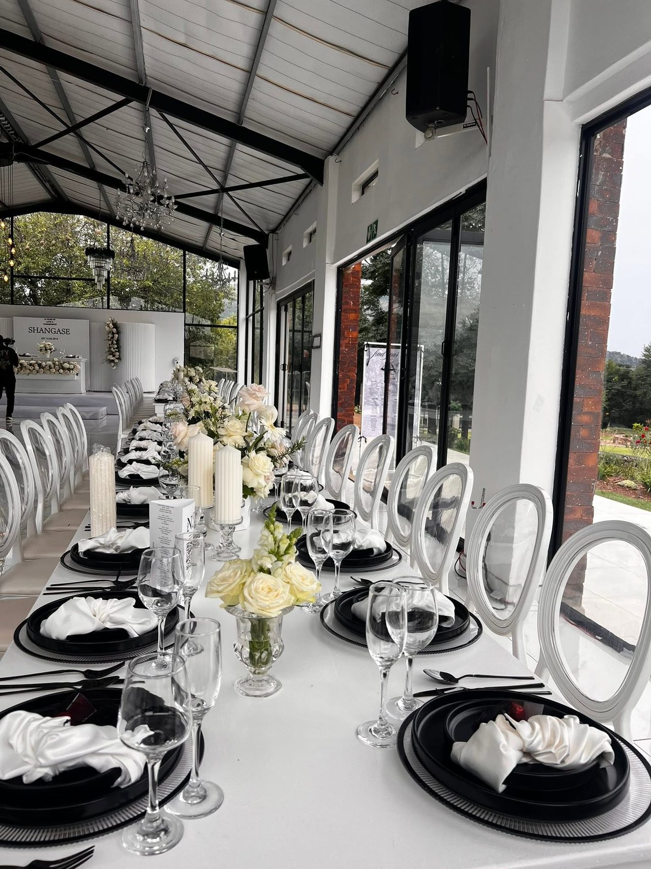 Banquet table with black chargers, white satin napkins, crystal glassware and ivory roses